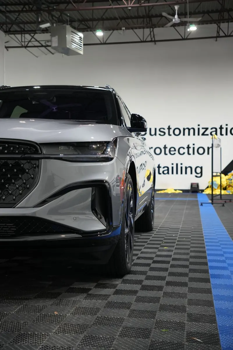 Vehicle parked in a shop bay, with wall lettering reading 'Customization,' 'Protection,' and 'Detailing' in the background.