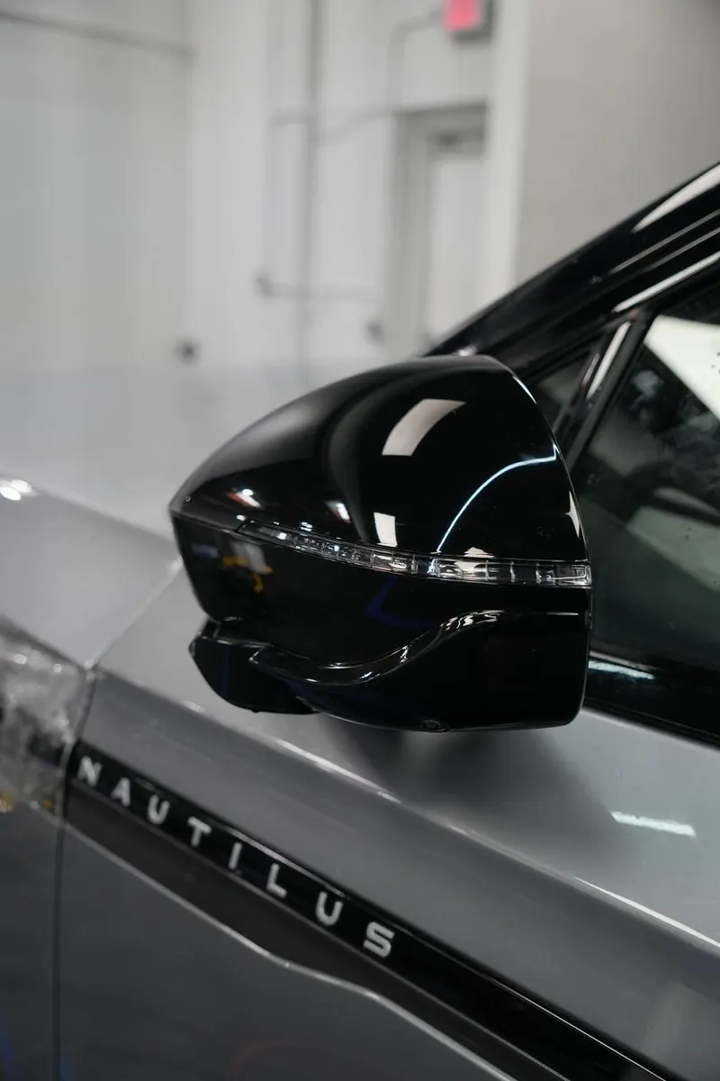 Close-up of a side mirror and 'Nautilus' badge on a vehicle's fender.